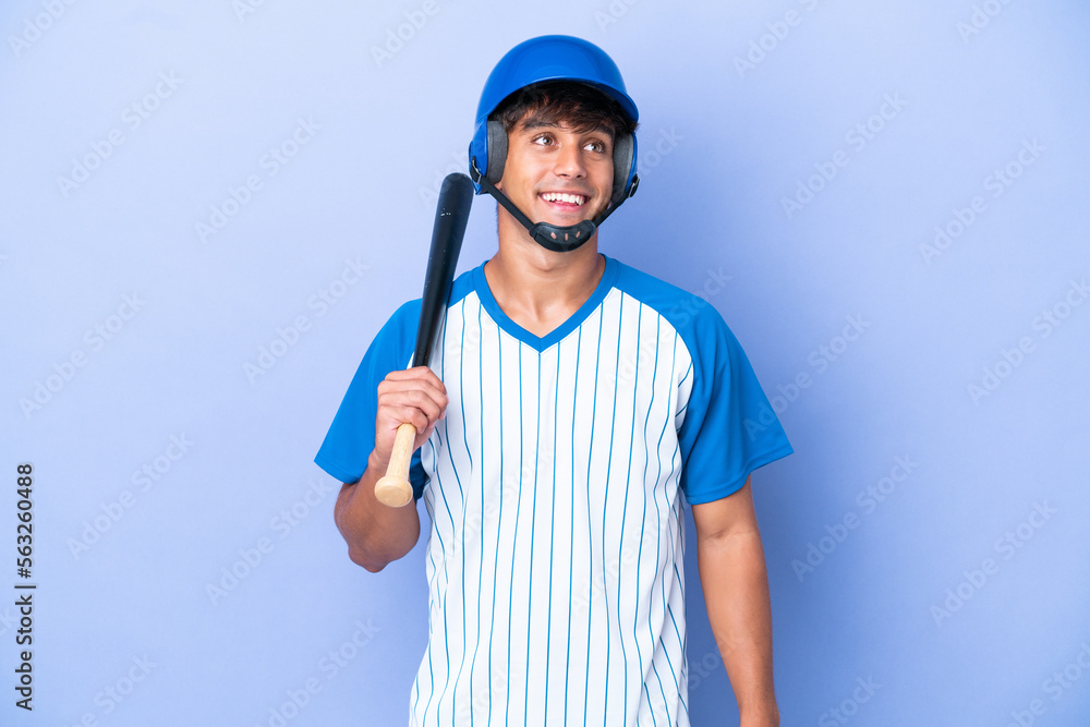 Baseball caucasian man player with helmet and bat isolated on blue background thinking an idea while looking up