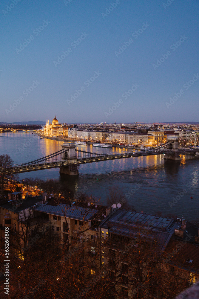 Fototapeta premium Night view of Budapest showcasing illuminated buildings, bridges, and reflections on the Danube River at dusk