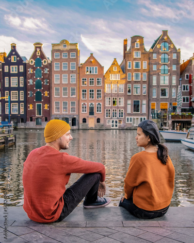 Photography Amsterdam Netherlands during Autumn fall season, a couple of men and a woman visit the city of Amsterdam with orange colors alongside the canal in October
