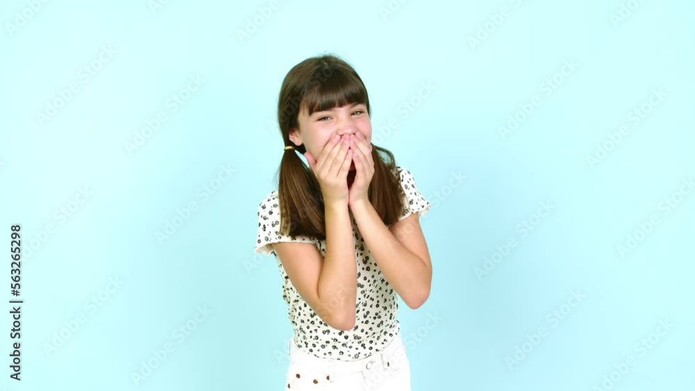 Little girl smiling a lot while covering mouth over isolated background Little girl smiling a lot while covering mouth over isolated background