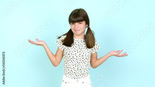 Little girl  making unimportant and doubts gesture while lifting the shoulders and the palms of the hands over isolated background