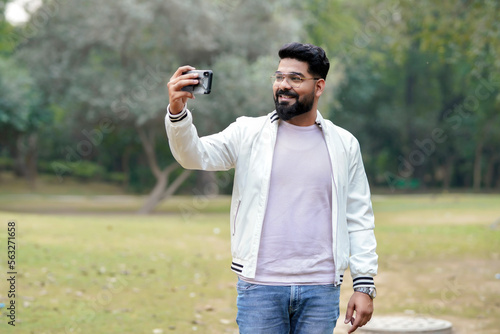 Young indian man using smartphone at park