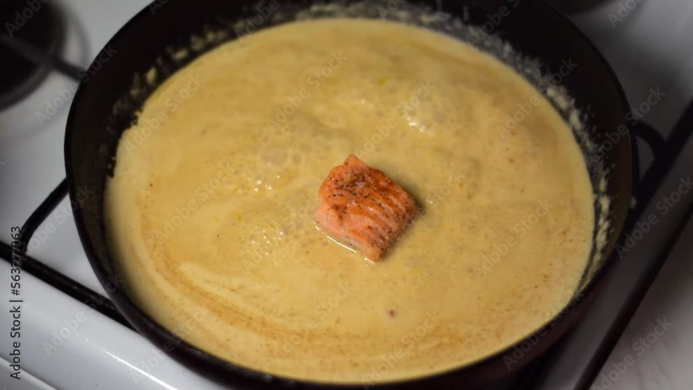 Putting trout fillet pieces into the sauce with coconut milk on the frying pan. Cooking fish curry. Asian cuisine meal Putting trout fillet pieces into the sauce with coconut milk on the frying pan. Cooking fish curry. Asian cuisine meal