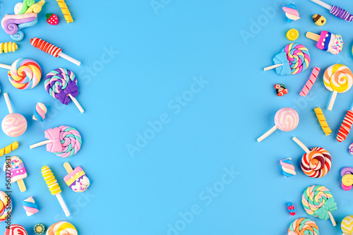 Frame made of decorative sweets, lollipops and ice cream. Top view on blue background