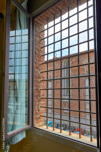 View on the old town of Siena through the widow with metal bars