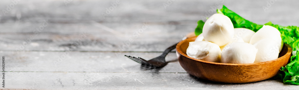 Mozzarella cheese in a wooden plate with lettuce. Mozzarella cheese in a wooden plate with lettuce.