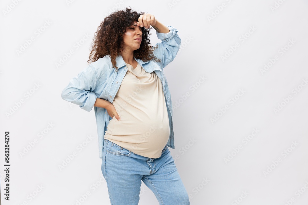 Fototapeta premium Pregnant woman tired, headache and abdominal pain, heavy pregnancy, last month before childbirth on white isolated background in T-shirt with blue shirt
