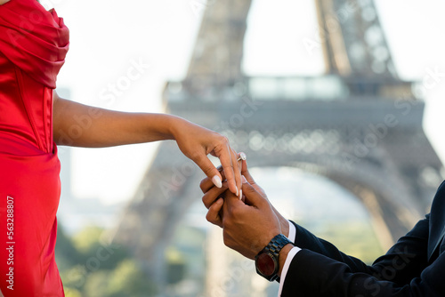 Photography Close up newly engaged couple putting an engagement ring on the finger, facing t