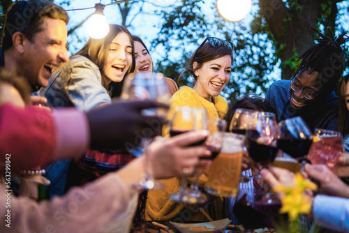 Diverse friends celebrate together at sunset toasting beers and wine - people lifestyle concept