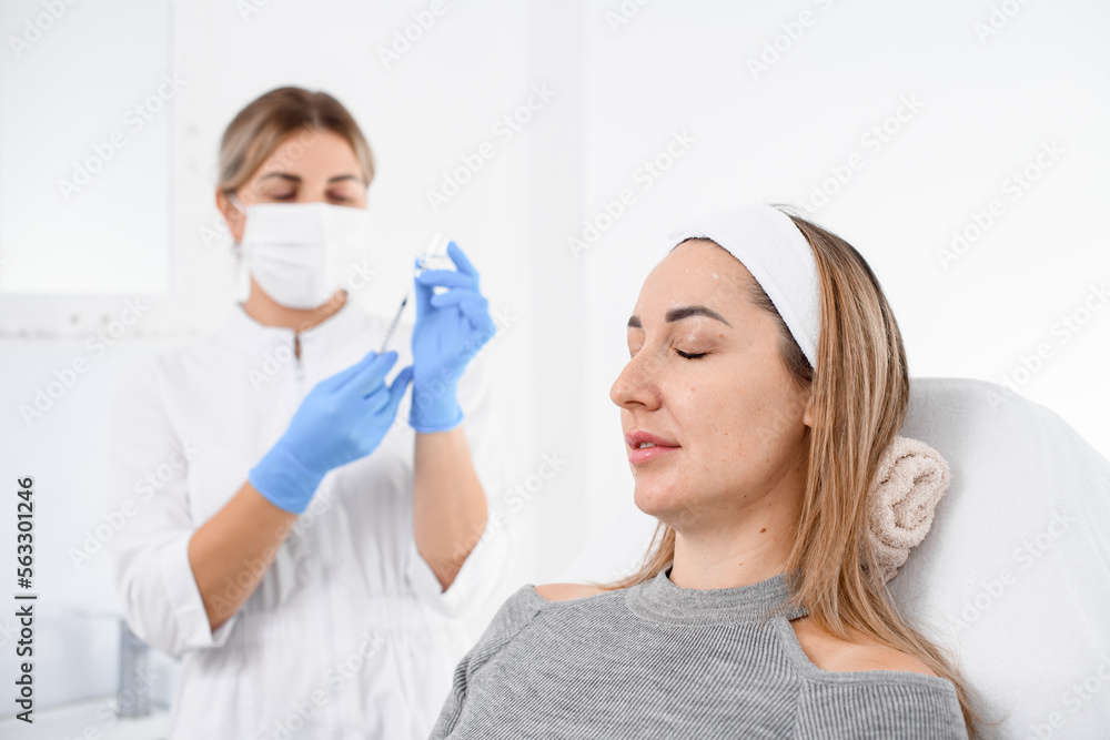 portrait of handsome female patient on couch and female cosmetologist in gloves on background. portrait of handsome female patient on couch and female cosmetologist in gloves on background.