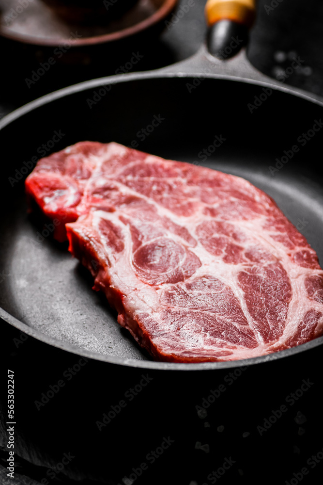 Raw pork steak in a frying pan. 