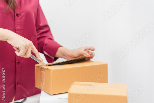 Asian women are using cutters on the adhesive tape to open the paper box, sell and buy online. © iSomboon