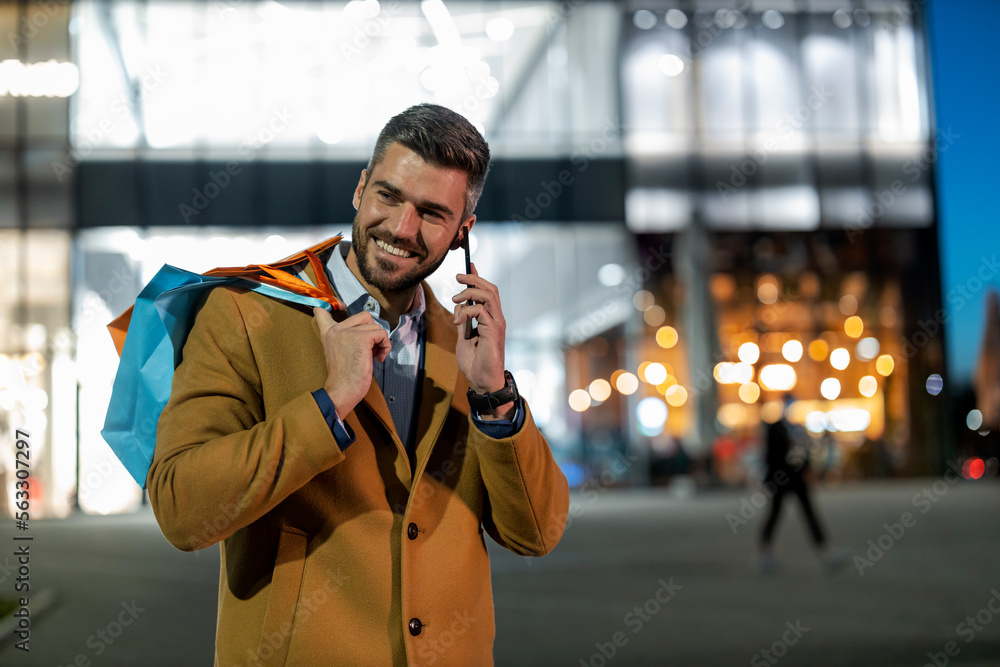 Young man using smart phone after shopping Young man using smart phone after shopping