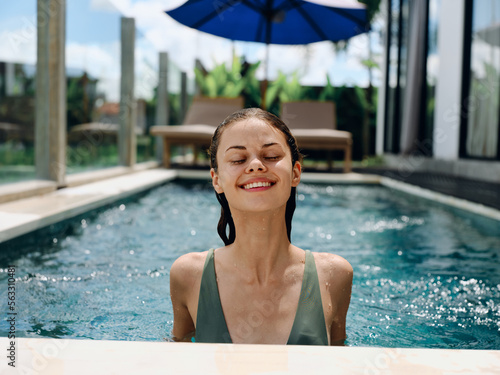 Portrait of a woman with closed eyes smile with teeth and laughing floats in the water in the pool in a swimsuit, summer vacation, holidays and travel to the tropics, beach lifestyle photo