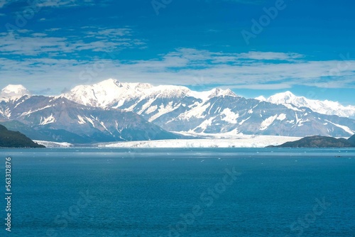 large vast mountain landscape in the distance showing water in foreground and blue skies during summer