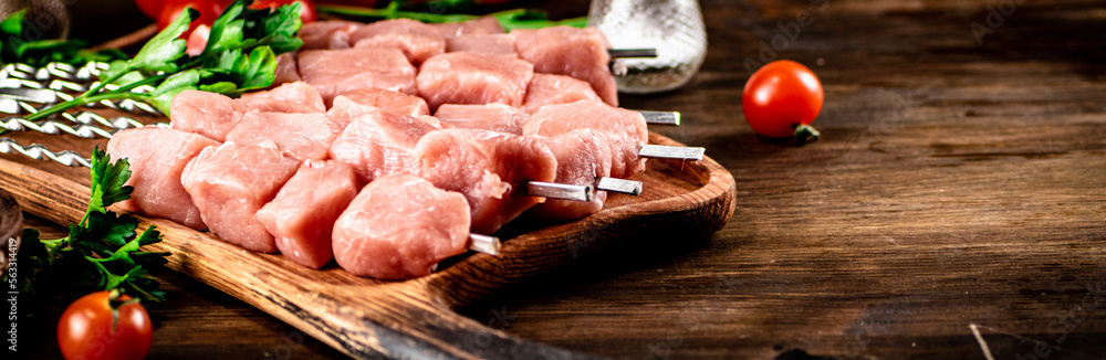 Pork kebab raw on skewers with parsley and tomatoes on a cutting board. Pork kebab raw on skewers with parsley and tomatoes on a cutting board.