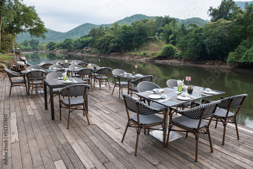 Fototapeta Naklejka Na Ścianę i Meble -  Outdoor restaurant table and chairs by kwai river, Kanchanaburi