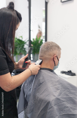 Woman hairdresser cuts man's hair in beauty salon