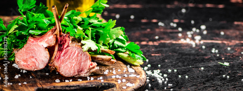 Rack of grilled lamb on a wooden cutting board with parsley. 