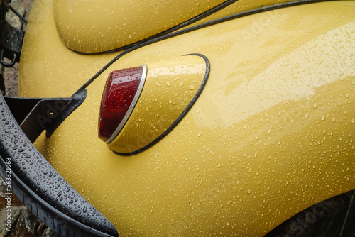 headlight and bumper of old beige beetle car, wet from raindrops