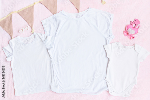 Mothers day mom and kids mockup white t-shirt and baby bodysuit onesie with heart on pink cover background. Flatlay, top view, copyspace. © lusyaya