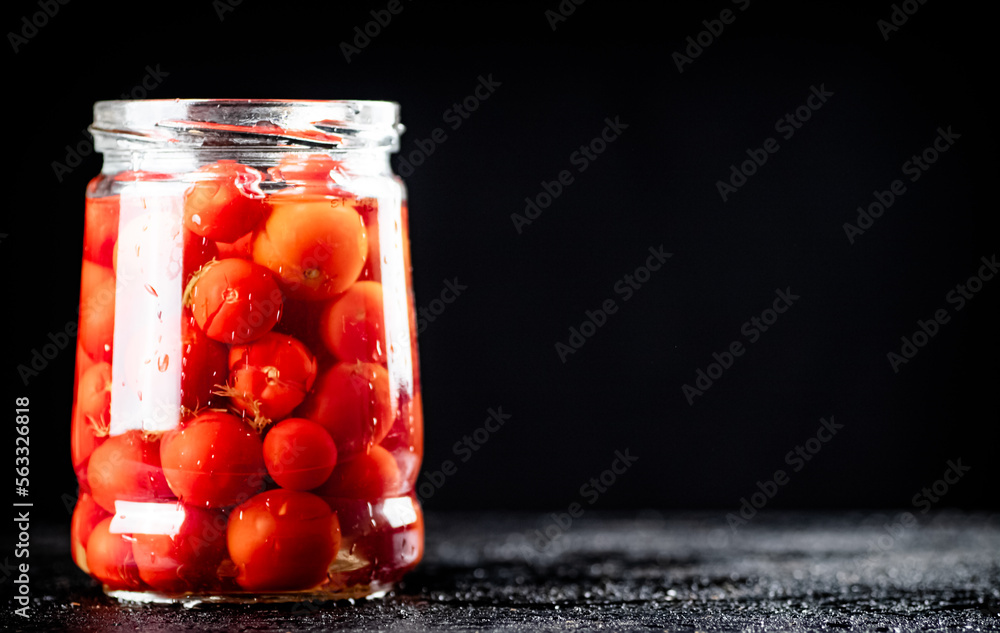 Pickled tomatoes in a glass jar on the table. Pickled tomatoes in a glass jar on the table.