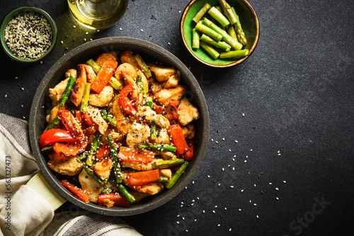 Chicken stir fry with vegetables at stone background. Top view with copy space.