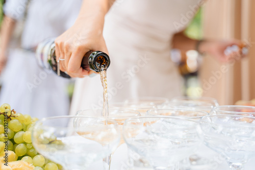 Pouring champagne into a glasses standing on table