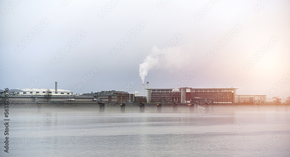 Fototapeta premium Factory over the river. Plant in Germany. Smoke from chimney industrial zone.