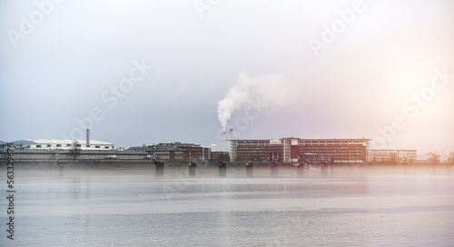 Factory over the river. Plant in Germany. Smoke from chimney industrial zone. © AlexGo