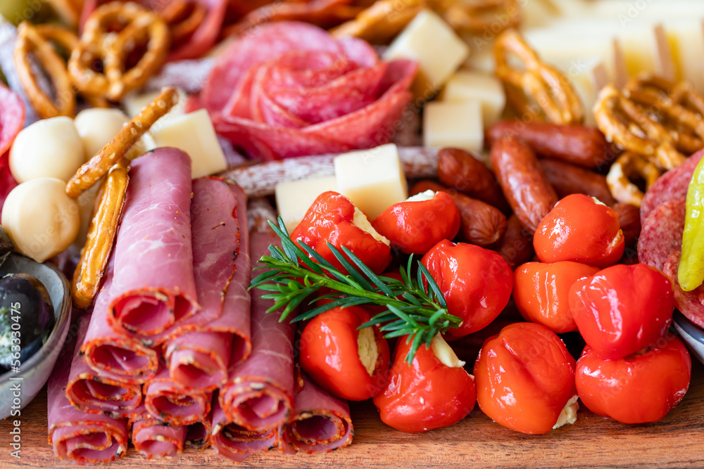 Cutting board with ham, salami, cheese, cracker and olives on a wooden board.