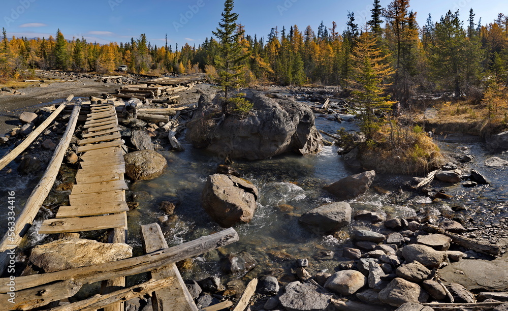 Russia. The Altai Mountains. A dilapidated wooden bridge over the Aktra River, which all-terrain vehicles drive around along the stone riverbed on the way to the ancient glacier of the same name.