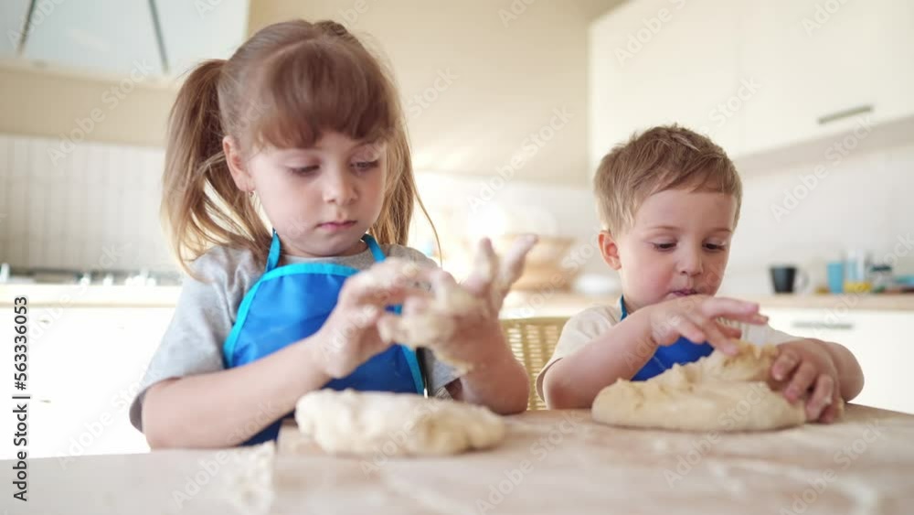 children making dough in the kitchen. baby boy cook in the kitchen knead dough and flour indoors. happy family lifestyle kid dream concept. children play cooking dough together at home children making dough in the kitchen. baby boy cook in the kitchen knead dough and flour indoors. happy family lifestyle kid dream concept. children play cooking dough together at home