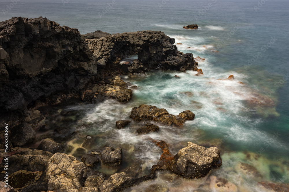 Obraz premium Rays of sunlight illuminating a volcanic cliff in the Atlantic Ocean.