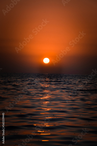 Fototapeta Naklejka Na Ścianę i Meble -  Vibrant sunset descending on the horizon, sea in golden colors, small waves gently touching the sands,