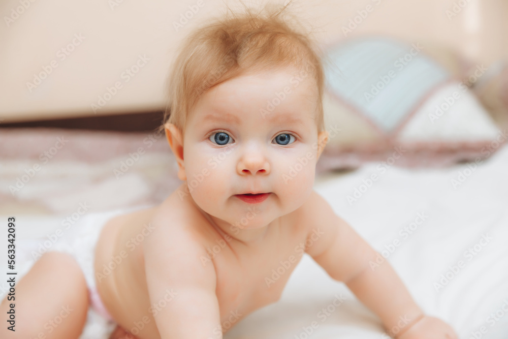 a funny baby crawling in the nursery at home. the baby is 6 months old learning to crawl