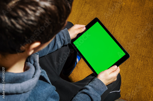A teenager sits and looks at a tablet, top view. Technology, chromakey
