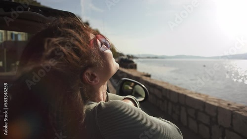 Beautiful girl have fun riding in convertible cabriolet car wearing heart-shaped glasses, freedom concept when hair fluttering in the wind. Summer Vacation at sea, in the mountains, on the coast. Car photo