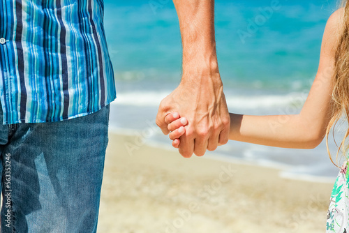 A Hands of a happy parent and child on the seashore on a journey trip in nature