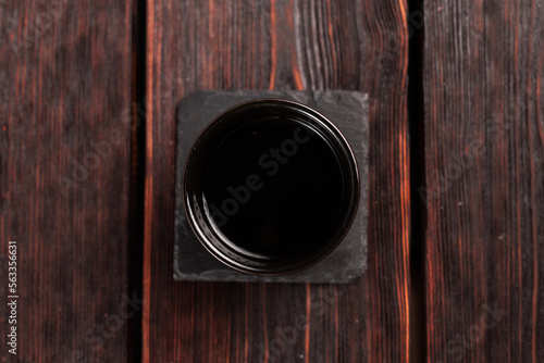 Bowl with soy sauce on wooden table, top view