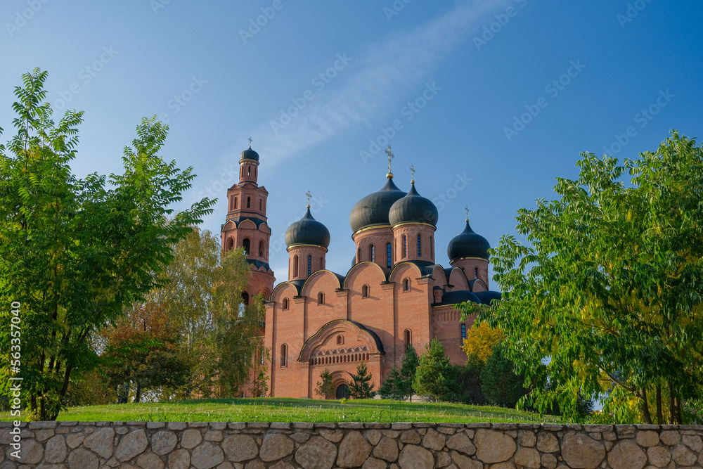 Orthodox church made of bricks view through the gate in summer