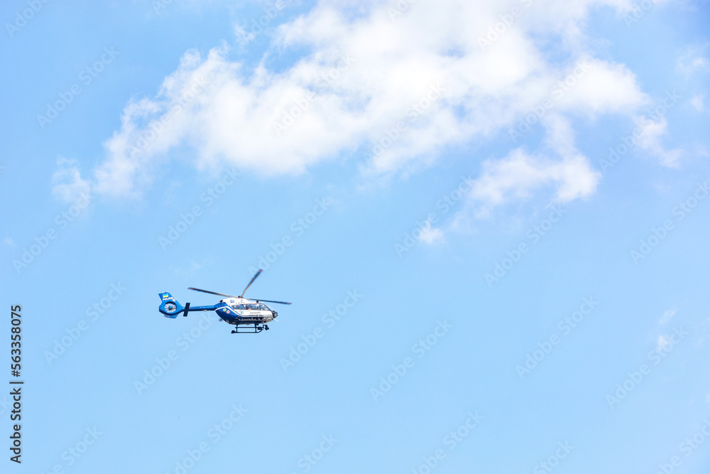 A flying police helicopter against a blue sky and a white cloud. A flying police helicopter against a blue sky and a white cloud.