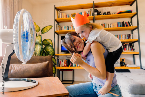 Girl cools off with mom in living room playing