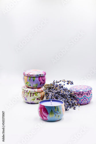 multicolored round lavender scented candles in metal boxes with a bouquet of dry lavender on a white background