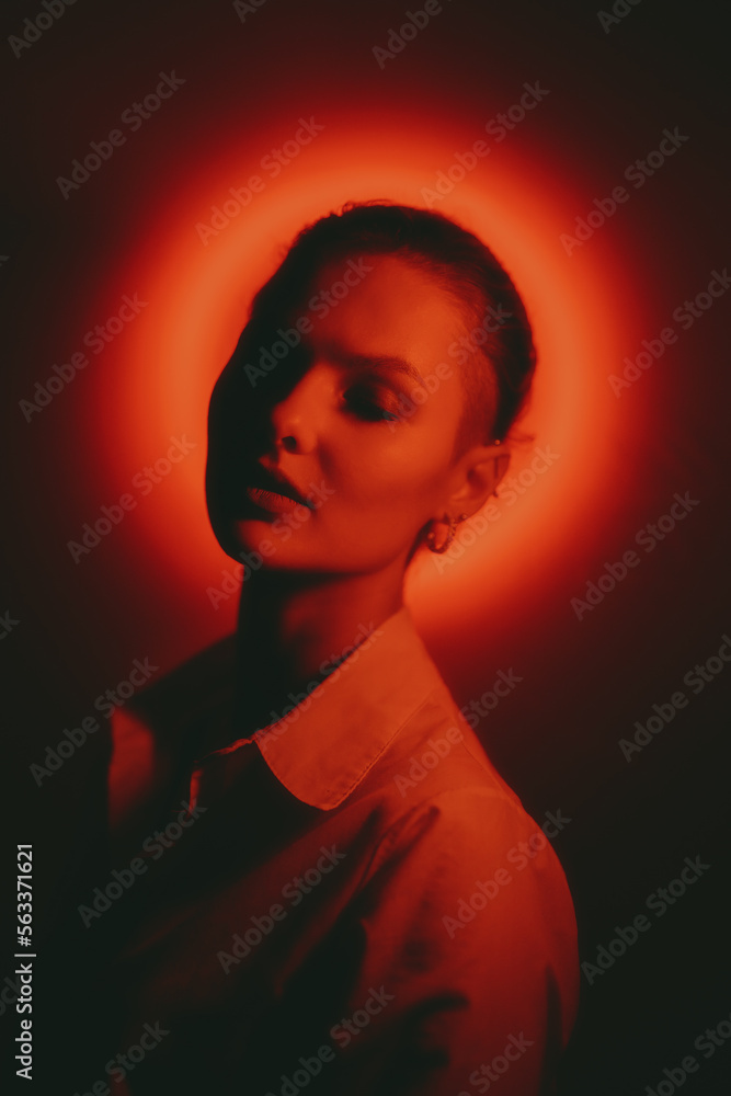 Woman portrait with glowing neon red circle on dark background Woman portrait with glowing neon red circle on dark background