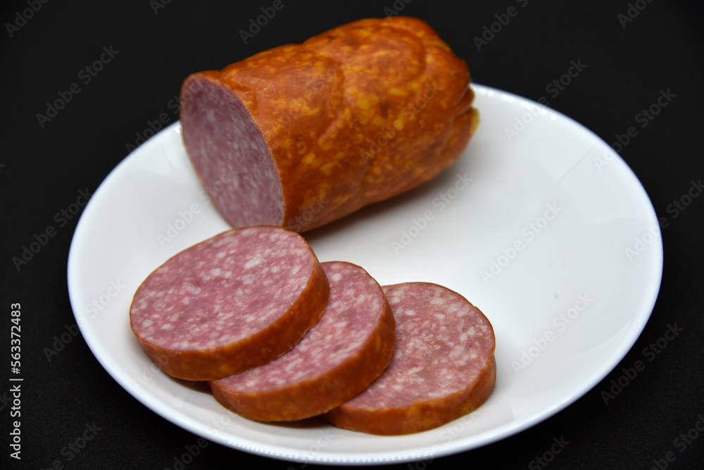 Delicious meat sausage on a white plate. Sliced ham. Slices of meat. Delicious meat sausage on a white plate. Sliced ham. Slices of meat.