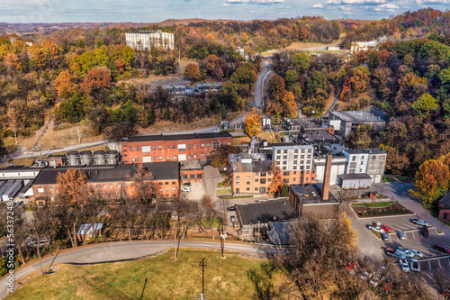 Aerial View of a historic bourbon whiskey distillery and an ageing warehouse on a hill in the background. Autumn colorful fall foliage panorama in Lynchburg Tennessee U.S.A.