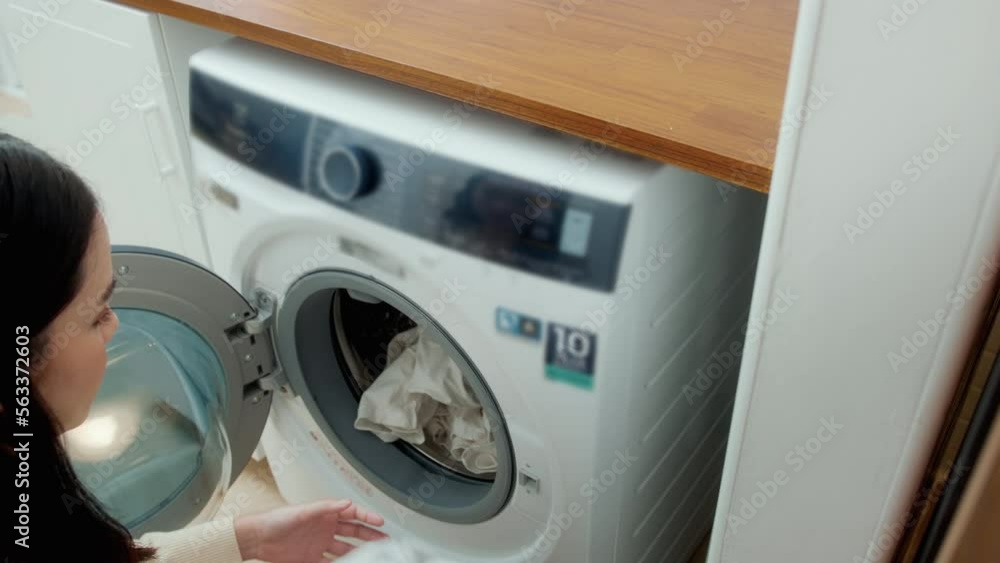 Close-up woman hand is keeping clothes in washing machine , health care lifestyle concept Close-up woman hand is keeping clothes in washing machine , health care lifestyle concept