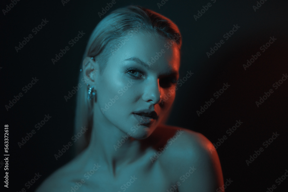 Fototapeta premium Fashion woman portrait on dark background with soft blue and red lights play on skin and copy space.