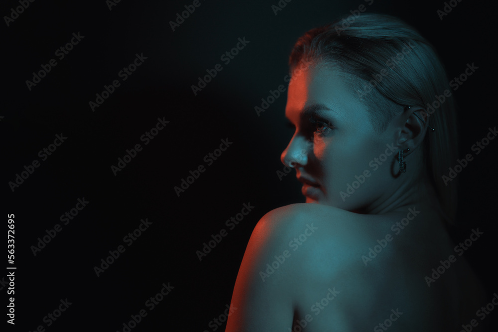 Fashion woman portrait on dark background with soft blue and red lights play on skin and copy space.